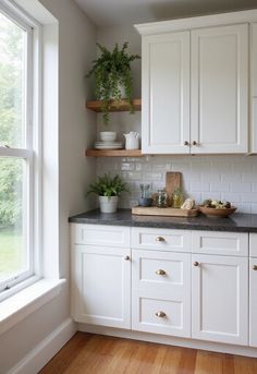 a kitchen with white cabinets and black counter tops next to a wooden window sill