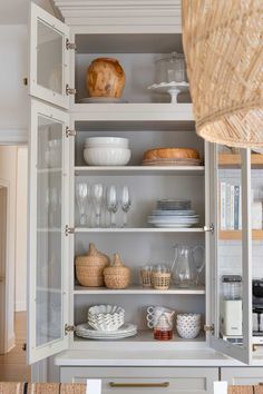 an open cabinet with dishes and glasses on it