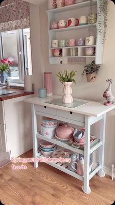 a table with plates and cups on it in a room that has pink flowers inside