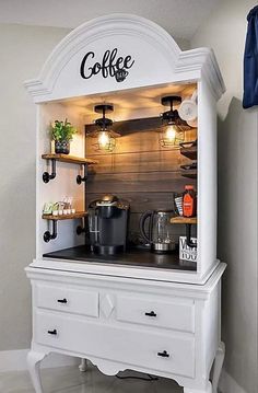 the coffee bar is built into an old dresser with lights on top and shelves above it
