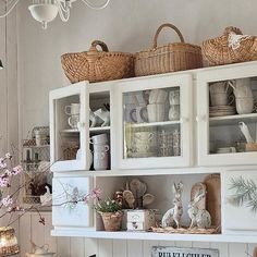 a white hutch filled with dishes and baskets