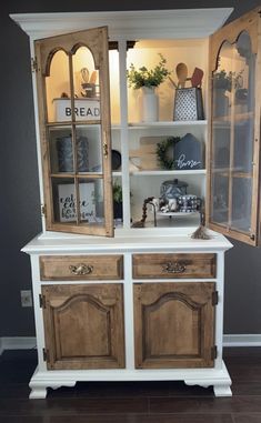 an old china cabinet is painted white and has wood trim on the doors, drawers, and shelves
