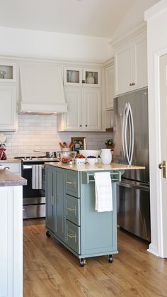 a kitchen with an island in the middle and stainless steel appliances on the other side